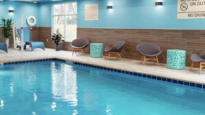 A swimming pool with blue tiles, surrounded by lounge chairs and potted plants. - Hampton Inn Tappahannock (Tappahannock)