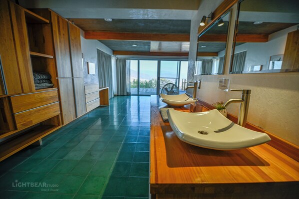 A modern bathroom with wooden cabinets, a large mirror, and a view of the outdoors.