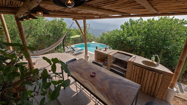 Un espacio al aire libre techado con piscina, barbacoa y zona de estar.