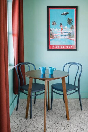 Un comedor con una mesa y sillas, un cuadro en la pared y una ventana con cortinas.