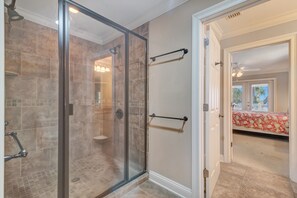 A modern bathroom with a glass shower enclosure, a towel rack, and a visible toilet.