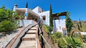 Un edificio blanco con una escalera de piedra que lleva a un porche cubierto.