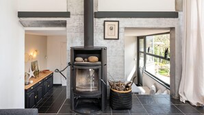 A modern interior with a stone fireplace, a black cabinet, and a window with a view of greenery.