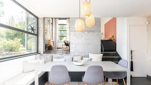 A modern dining area with a large table, grey chairs, and a white bench.