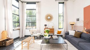 A modern living room with a sofa, coffee table, and a large window with curtains.