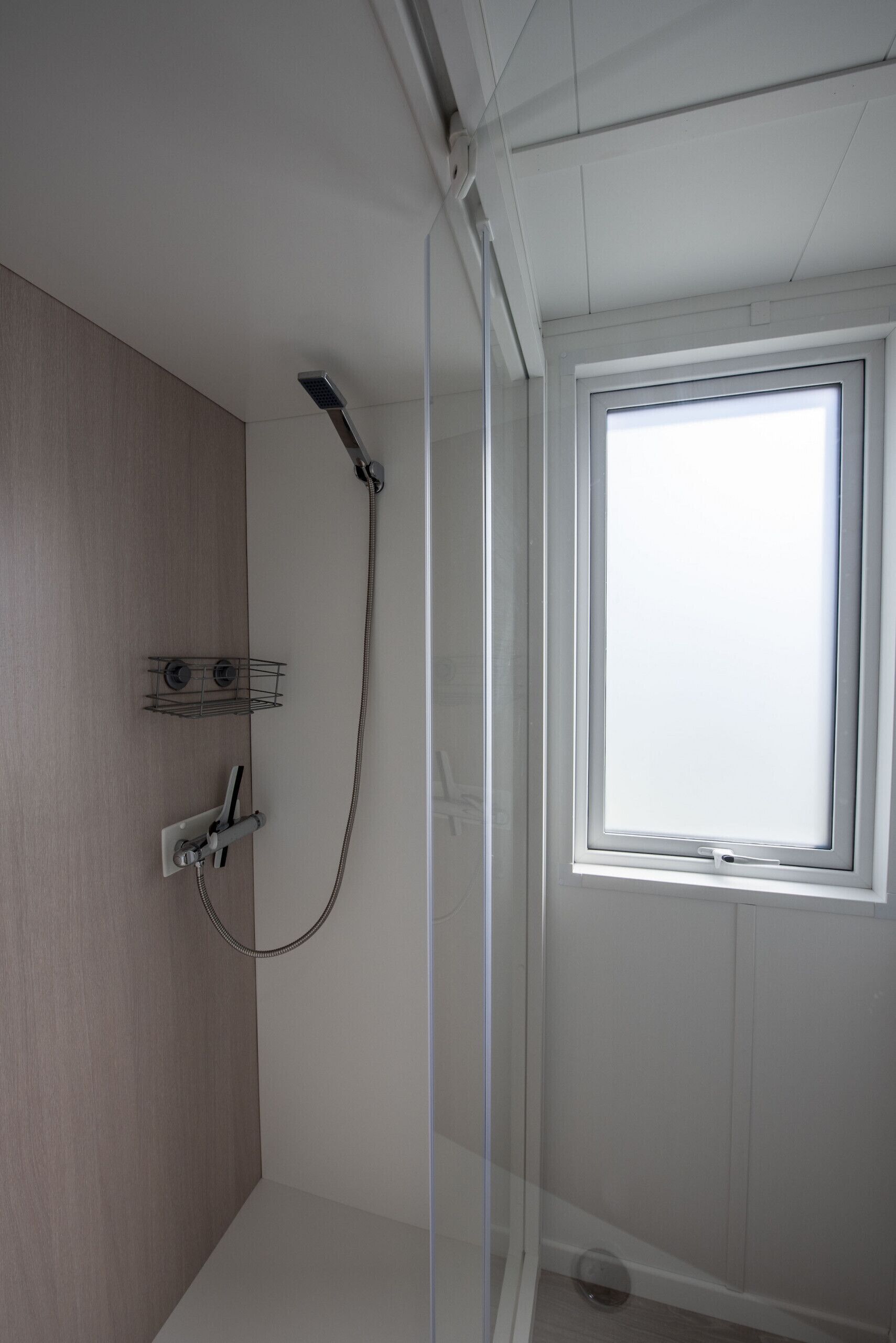 A shower with a handheld showerhead and a wall-mounted faucet.
