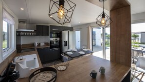 A modern kitchen with a wooden countertop, a dining area with a table set for four, and a large window providing a view of the outdoors. - Chalet for 6 in an estate with swimming pool (Bretignolles-sur-Mer)