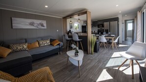 A modern living room with a sofa, coffee table, and dining area. - Chalet for 6 in an estate with swimming pool (Bretignolles-sur-Mer)