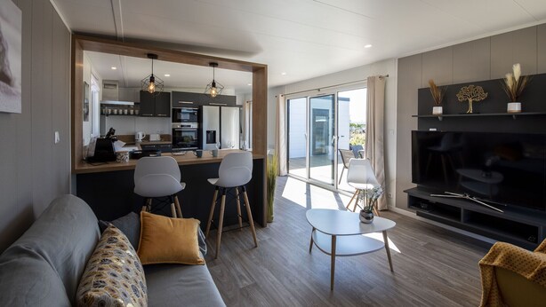 A modern living room with a sofa, a dining area, and a kitchen. - Chalet for 6 in an estate with swimming pool (Bretignolles-sur-Mer)