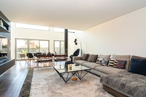 Een moderne woonkamer met een glazen salontafel, een bank met opvallende kussens en een eethoek met stoelen en een tafel.
