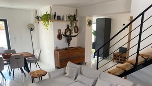 Ein modernes Wohnzimmer mit einem Ecksofa, einem Holztisch und einer Treppe mit schwarzer Geländer.