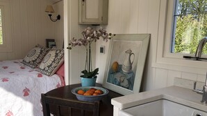 Une chambre à coucher avec un lit, une table de chevet sur laquelle se trouve un bol de fruits, une orchidée en pot et un tableau.