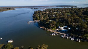 An aerial view of a coastal area with a marina, boats, and a large house with a unique architectural design. - Bliss by the Bay: Located along the beautiful Metung foreshore walks (Metung)