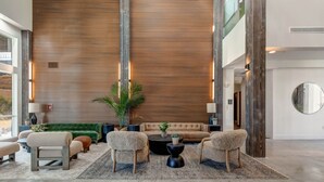 A spacious living area with a high ceiling, a large wooden panel wall, and a modern sofa set.