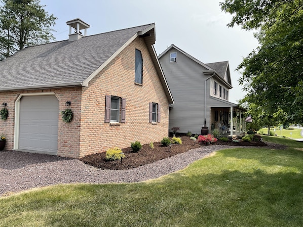 A two-story house with a brick facade, a garage, and a covered porch with an American flag.