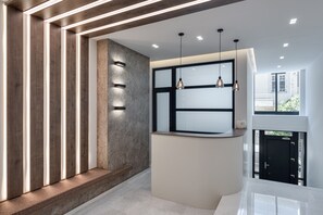 A modern reception area with a counter, wooden paneling, and pendant lighting. - Athenian Spirit (Athens)