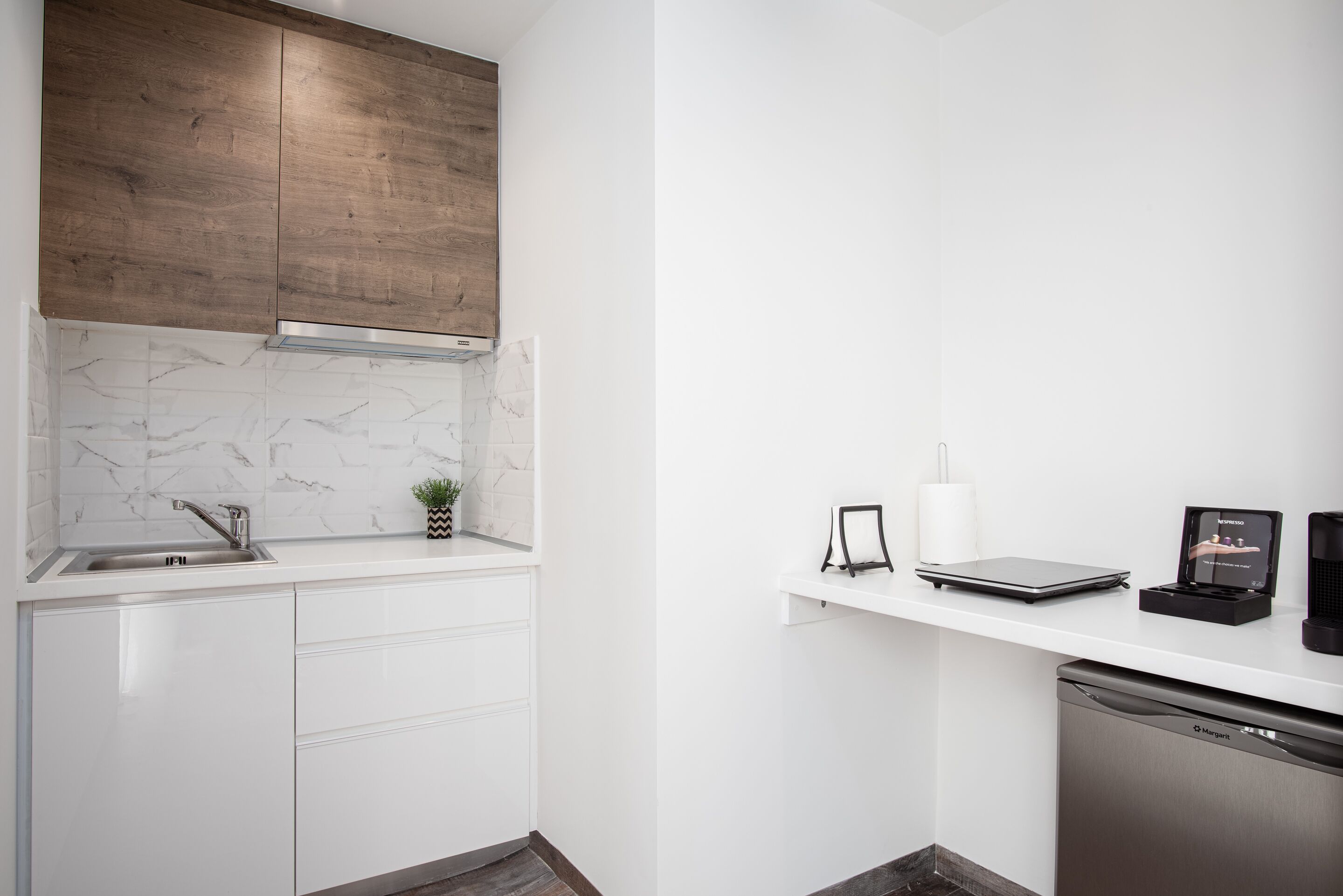 A modern kitchen with white cabinetry, a marble backsplash, and a wooden upper cabinet.