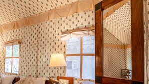 A cozy room with a bed, a wooden cabinet, a table, and patterned wallpaper. - Ranthambore Tiger Resort by Park Tree (Sawai Madhopur)