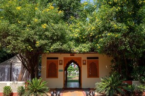 An entrance with an archway, surrounded by lush greenery and yellow flowers. - Ranthambore Tiger Resort by Park Tree (Sawai Madhopur)