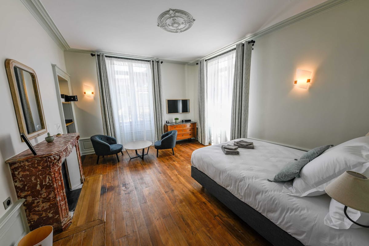 Une chambre d’hôtel avec un grand lit, un bureau, une chaise, une télévision et une cheminée.