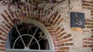 A brick building with a large arched window and a sign with a stylized 'A' on the wall. - Maison Qualisterra - Chambre d'Hôtes (Bar-sur-Aube)