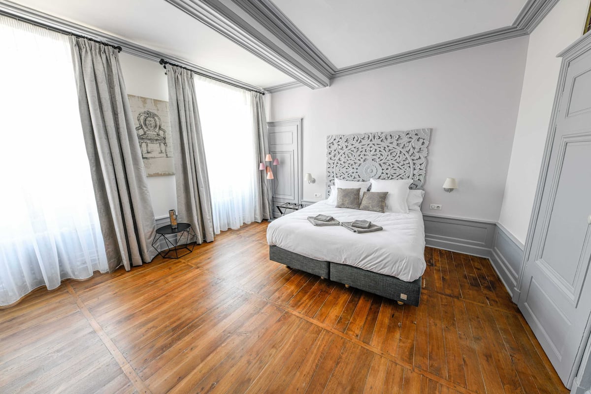 Une chambre à coucher avec un grand lit, un plancher en bois et une tête de lit décorative.