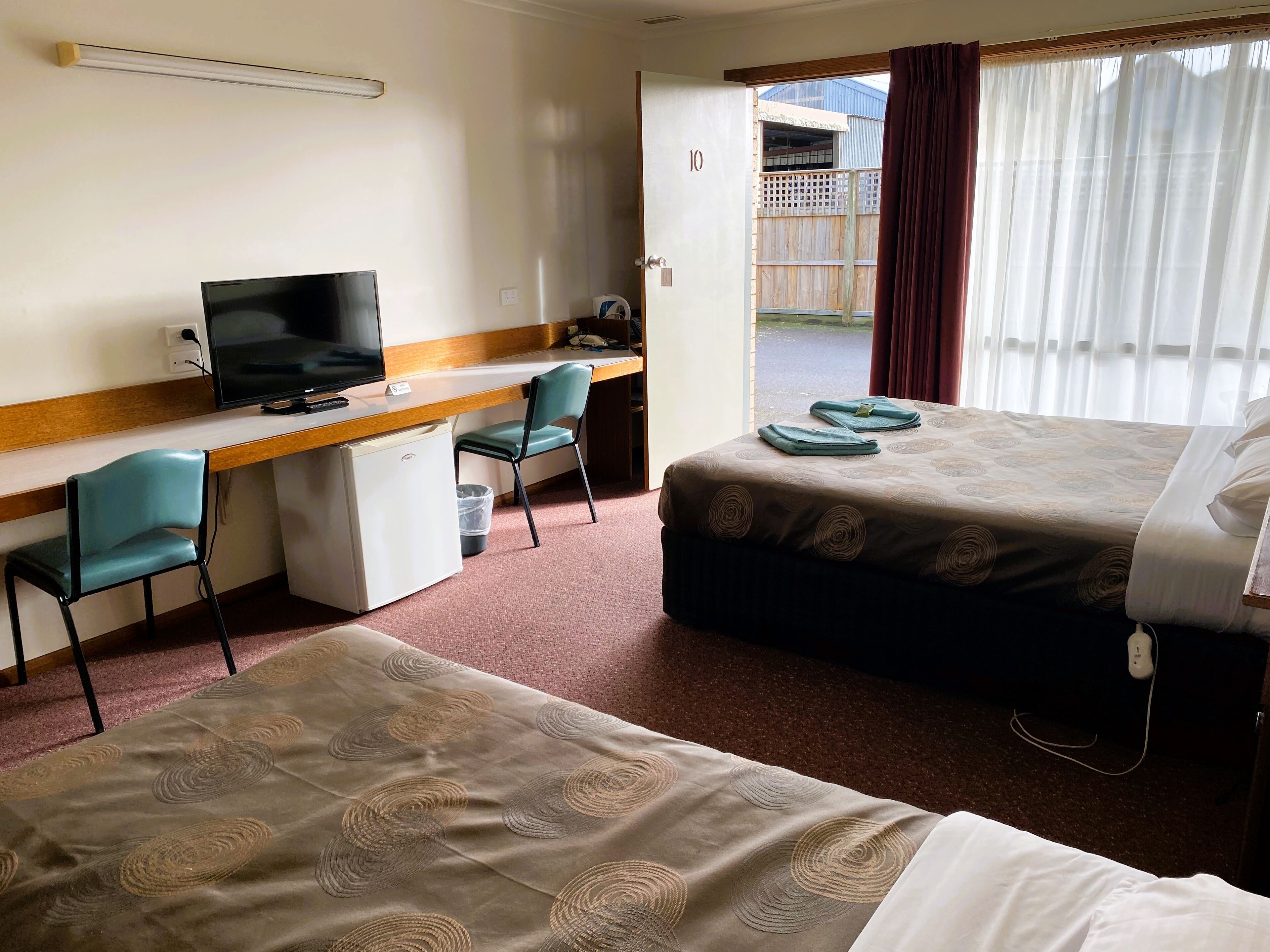 Een hotelkamer met een bureau, een televisie, een bed en uitzicht.
