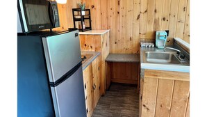 A compact kitchen with a refrigerator, microwave, coffee maker, and sink.