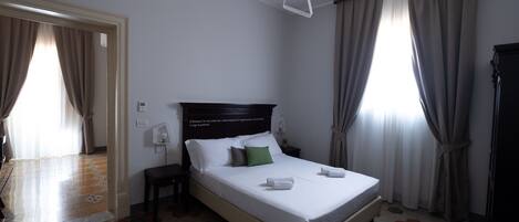 Quarto de hotel com cama, mesa de cabeceira, cadeira e guarda-roupa.