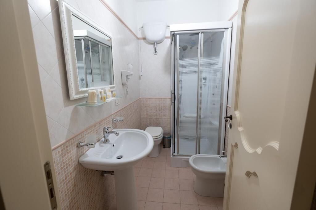 Un bagno piccolo ma funzionale, con lavandino, WC e box doccia in vetro.