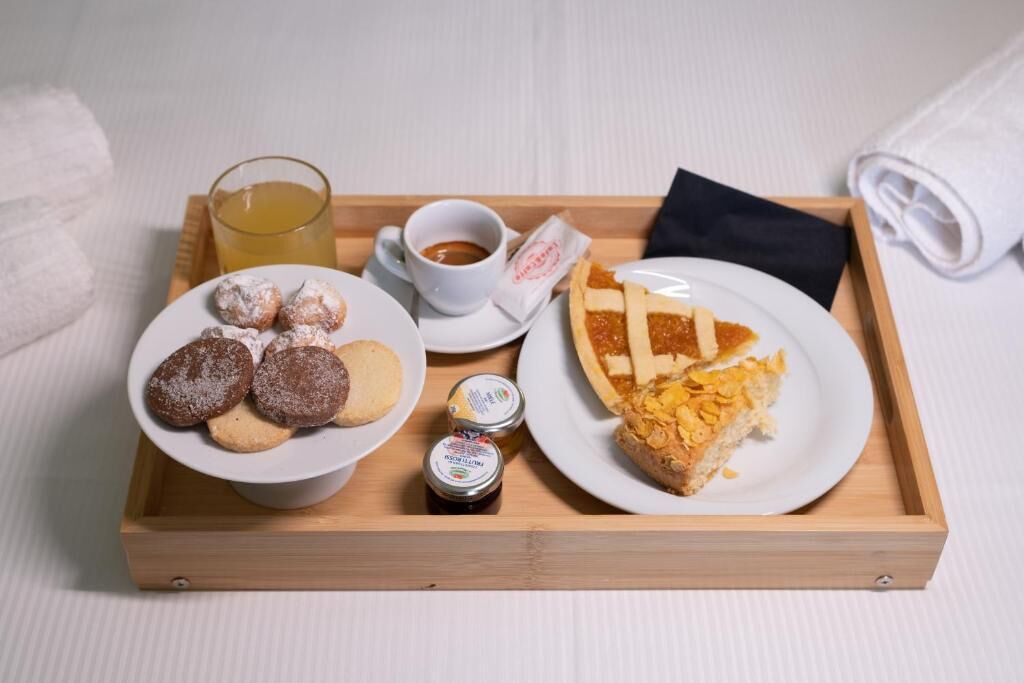 A tray with pastries, a slice of pie, a cup of coffee, and a glass of juice.