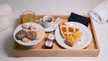 Eine Schale mit Gebäck, ein Stück Kuchen, eine Tasse Kaffee und ein Glas Saft.