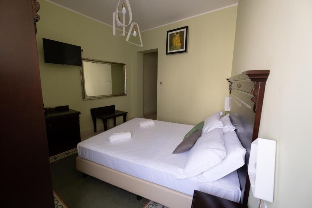 Ein Hotelzimmer mit Bett, Schreibtisch, Stuhl, Fernseher und Spiegel.