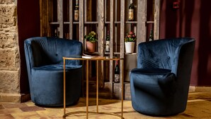 Two blue velvet armchairs, a small round table with a gold base, and a wooden bookshelf with various items. - Borgo di Ciàula (Santa Flavia)