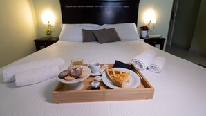 A neatly made bed with a tray of breakfast items including pastries, a cup of coffee, and a slice of pie. - Borgo di Ciàula (Santa Flavia)