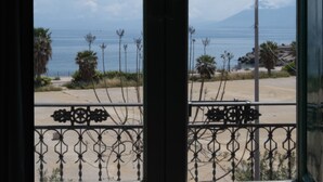 A view through a window with a metal railing, a clear sky, and a distant view of the sea and a mountain. - Borgo di Ciàula (Santa Flavia)