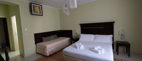 A hotel room with a large bed, a smaller bed, and a desk.