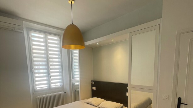 A bedroom with a bed, a radiator, a window with blinds, a door, and a light fixture. - T2 41 m2 CANNES bas SUQUET with parking, near beach and town center (Cannes)