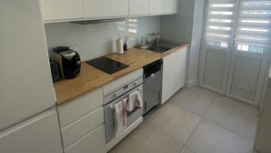 A modern kitchen with white cabinets, a wooden countertop, a built-in oven, and a dishwasher. - T2 41 m2 CANNES bas SUQUET with parking, near beach and town center (Cannes)