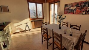 A dining area with a table set for four, a radiator, a window with a view, and a painting on the wall. - Private garden, tranquility and privacy (San Michele-montecchio)