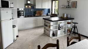 A modern kitchen with white cabinets, a black countertop island, and a built-in oven. - Private garden, tranquility and privacy (San Michele-montecchio)