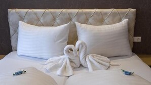 A hotel room with a tufted headboard, two pillows, and two towels arranged on the bed. - Four-bed room with bath, WC - B&B - Golf- und Skipension Krug (Haus)