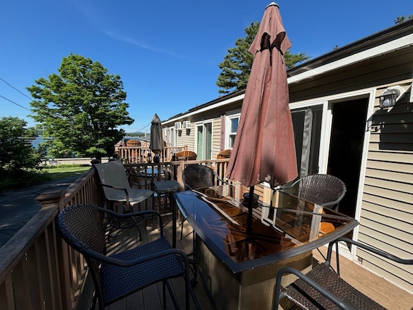 Eine Terrasse mit Gartenmöbeln, darunter Stühle und ein Tisch, sowie ein großer Sonnenschirm.