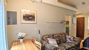 A living room with a patterned sofa, a wooden dining table, and a framed picture on the wall. - Hi Spot Studio with shared beach on Winnipesaukee! (Laconia)