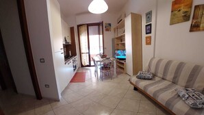 A living room with a sofa, a television, and a dining area with a table and chairs. - FURNISHED TWO-ROOM APARTMENT 200 MT FROM THE LIDO OF ALGHERO (Alghero)