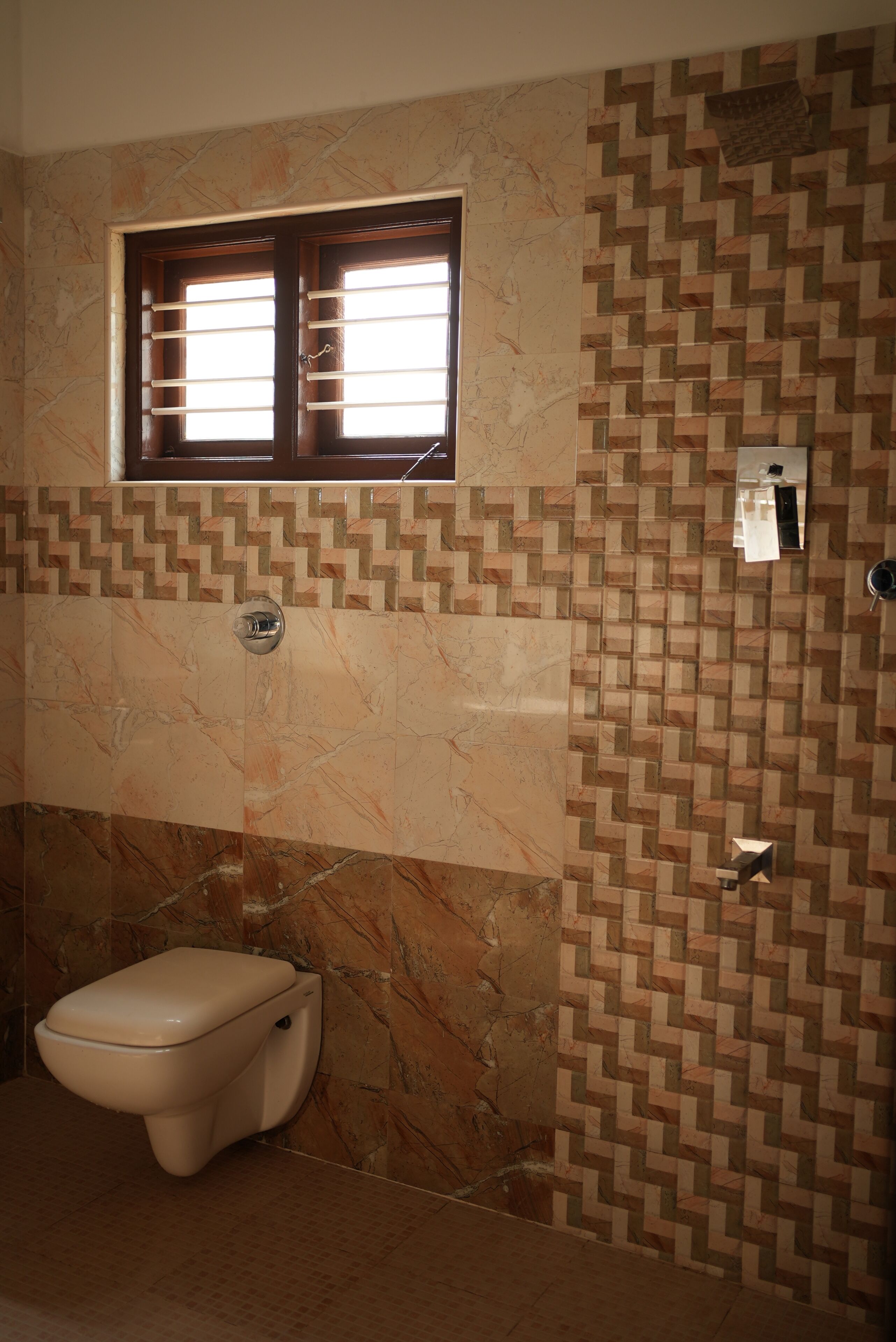 Un baño con inodoro, ventana y pared con diseño.
