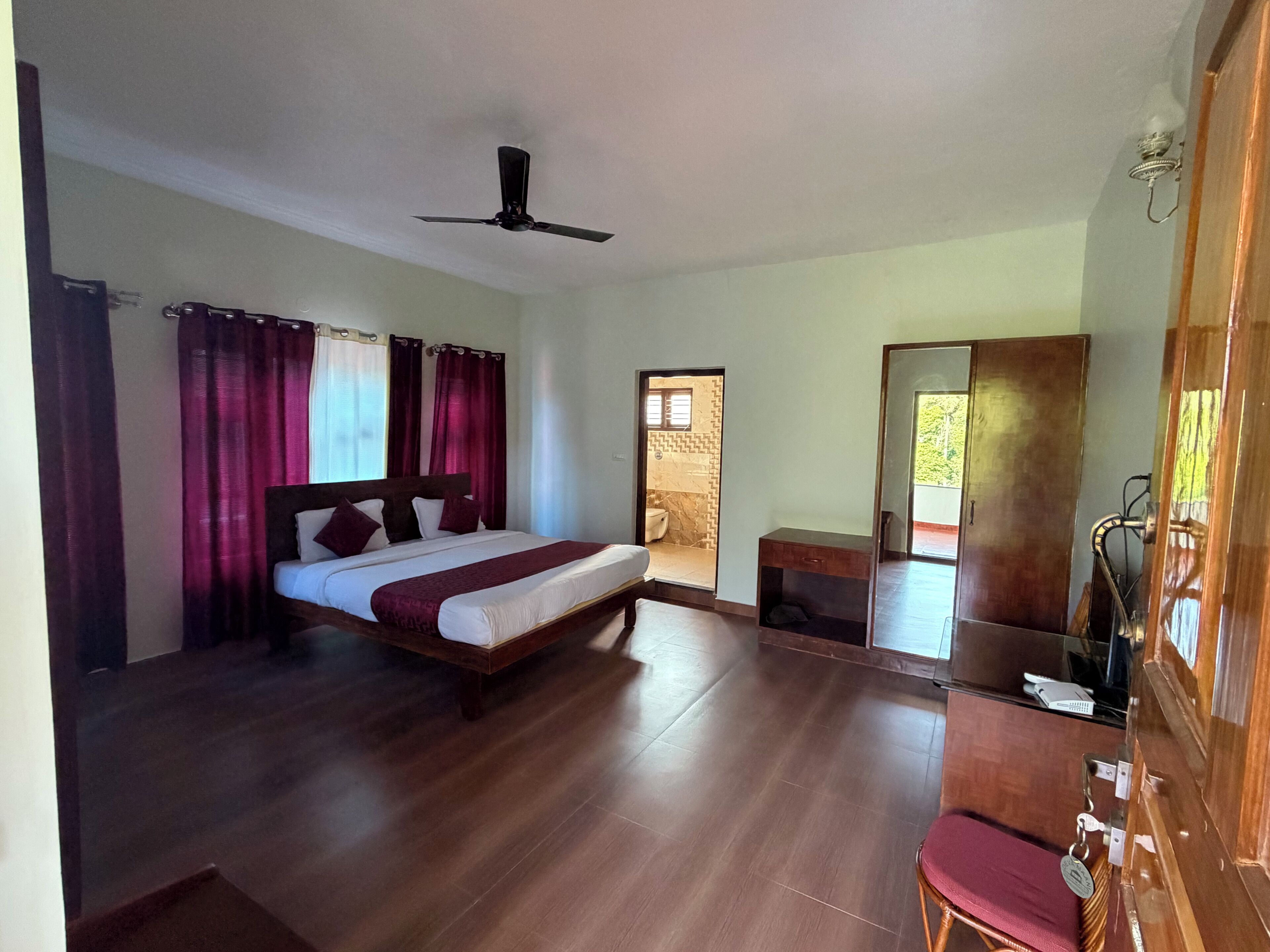 A bedroom with a bed, a desk, a chair, a wardrobe, and a ceiling fan.