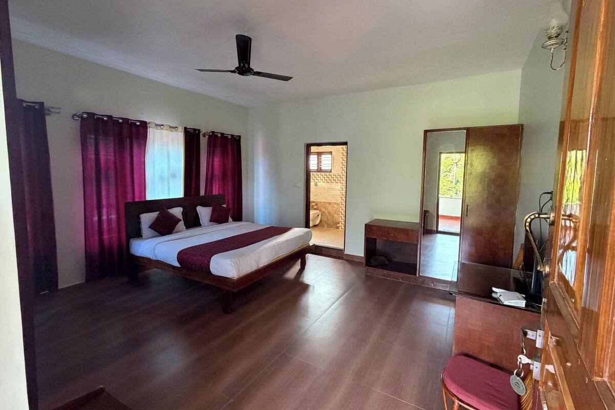 Une chambre à coucher comprenant un lit, un bureau, une chaise, une armoire et un ventilateur de plafond.
