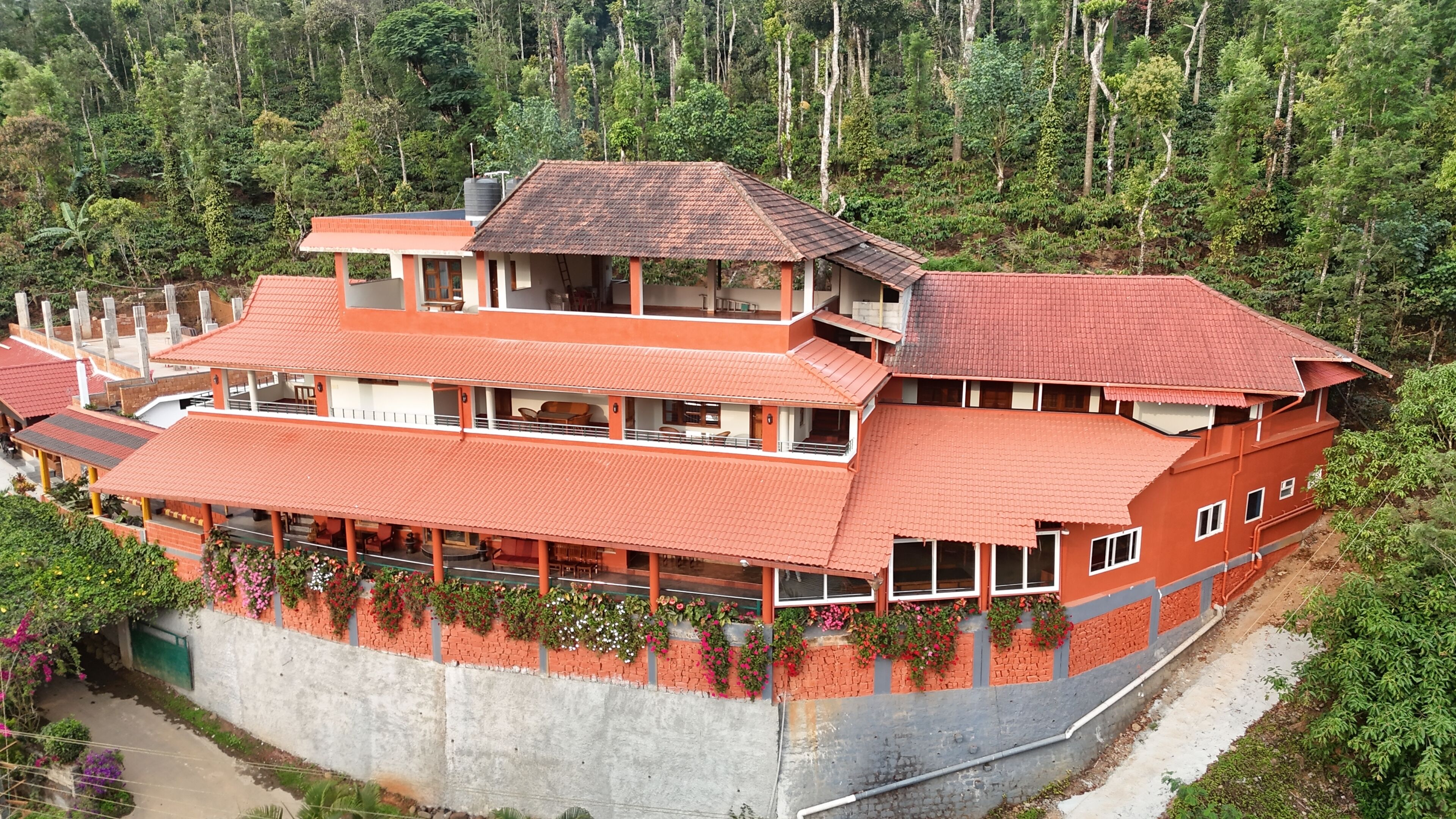 A multi-story building with a red roof, surrounded by lush greenery.
