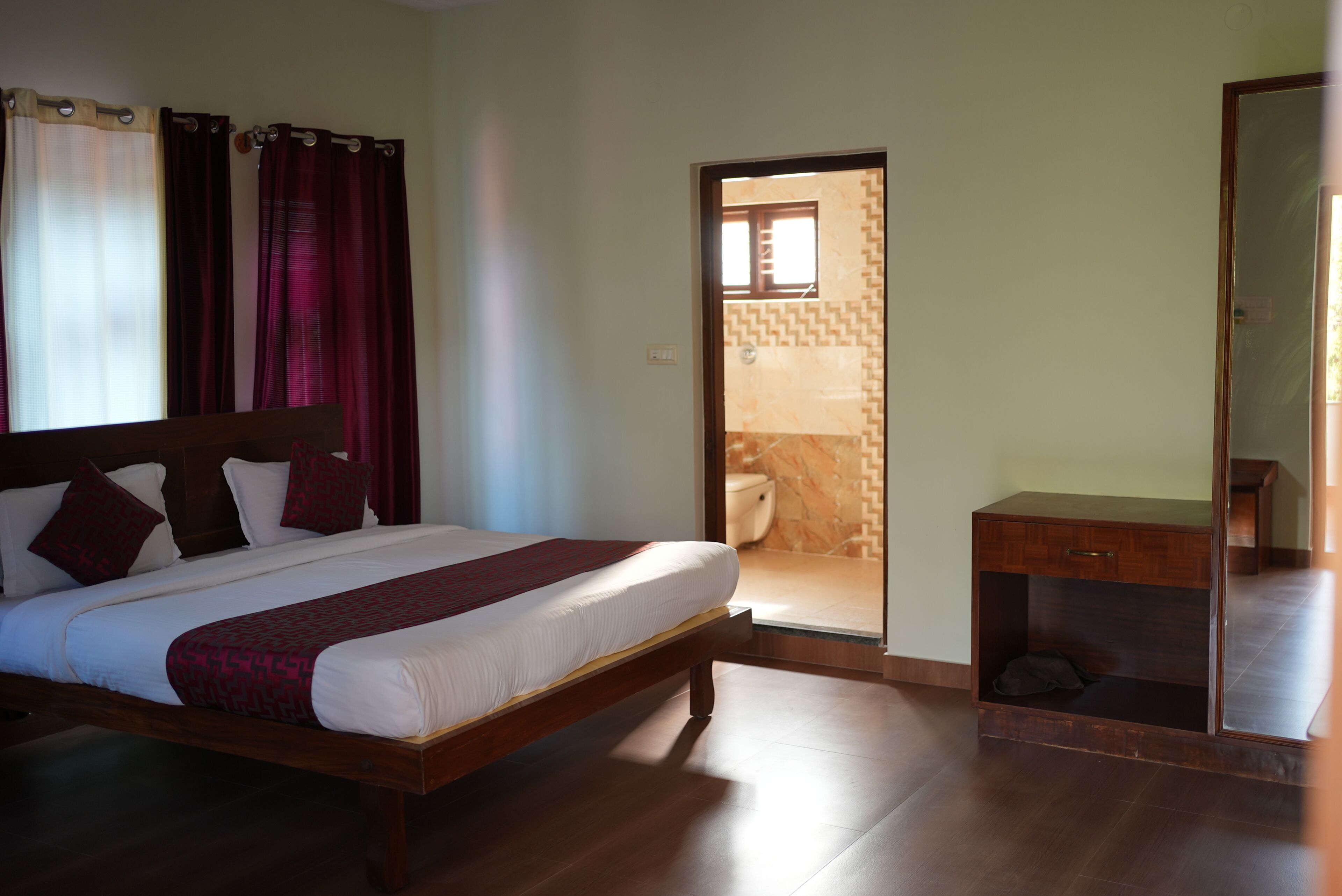 Ein Schlafzimmer mit Bett, Nachttisch, Spiegel und einer Tür zum Badezimmer.